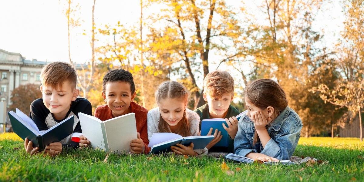 Cute little children reading books in park